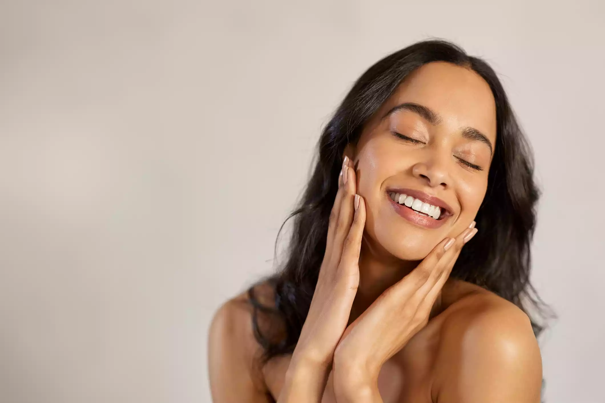 Woman caressing her face, signifying self-care and skin rejuvenation efforts.