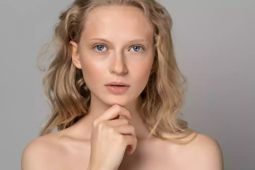 Close-up of young woman with natural beauty, blue eyes, and curly blonde hair.