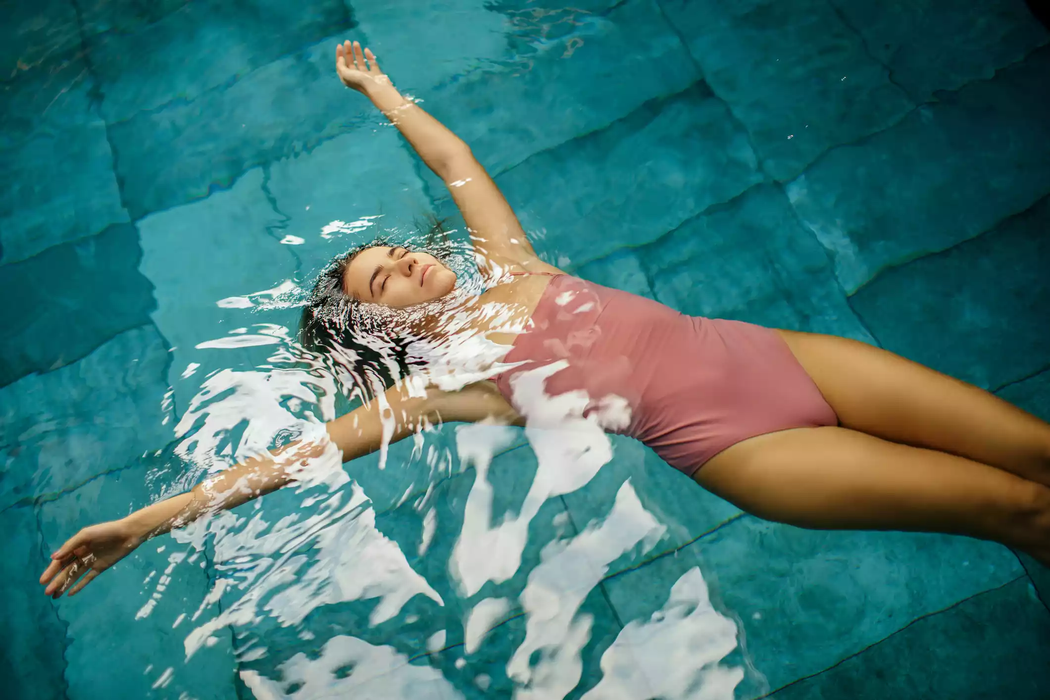 Content woman floating in refreshing pool water